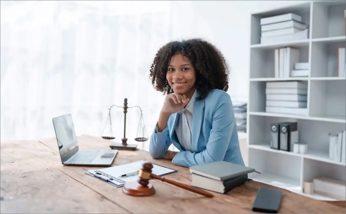 Mujer egresada de la Carrera de Derecho sentada frente a un escritorio con una laptop en oficina